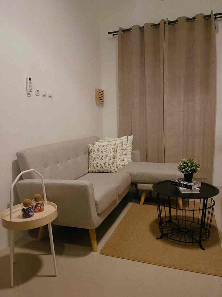 Beige and gray toned living room featuring a gray sofa, beige curtains, and carpet creating a warm, cozy atmosphere