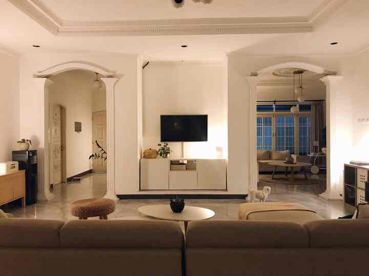 White-walled mid-century modern living room for 4 persons featuring wooden furniture, warm ambient lighting, and a small dog