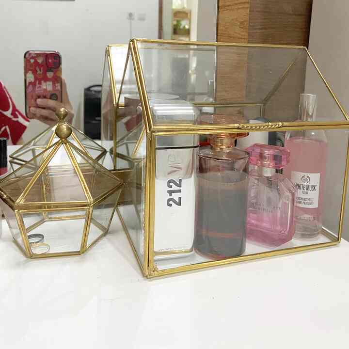 Minimal vanity space featuring transparent gold-framed storage boxes on a white table