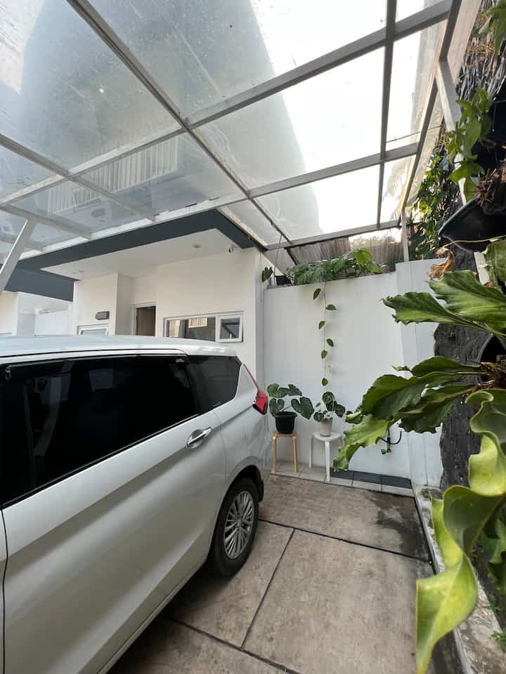 Carport minimalis yang didesain dengan atap SolarFlat bening yang menciptakan nuansa terang, penyimpanan sepatu yang tertutup, serta dekorasi sederhana dengan tanaman yang kuat akan sinar matahari terang #carport #kanopi #houseplants