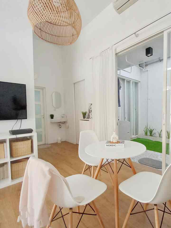 Bright and spacious living and dining area in white and wood tones featuring a round table, chairs, and sliding door to balcony