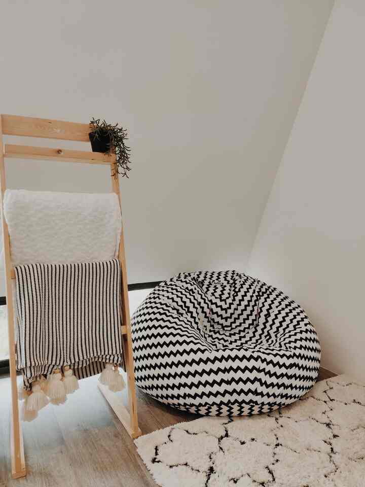 Natural white-toned balcony space featuring wood tone ladder hanger and zigzag patterned bean bag chair