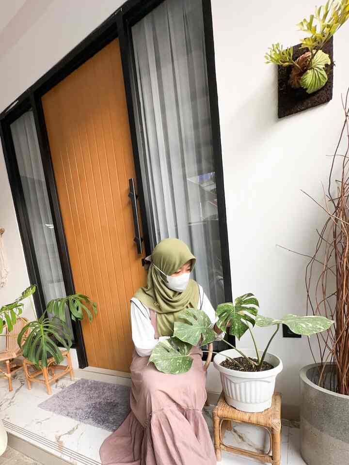 Wood tone entrance area featuring rattan chair and various plants with a cozy atmosphere