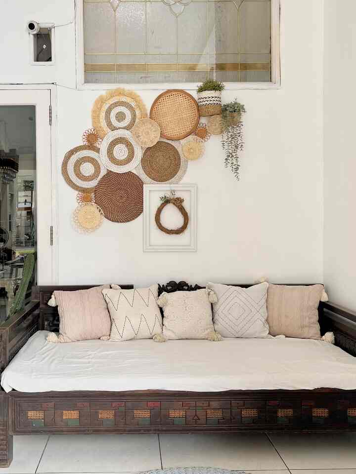 Natural wood tone and white background living room featuring a bohemian style wall tray decor and cushions on sofa