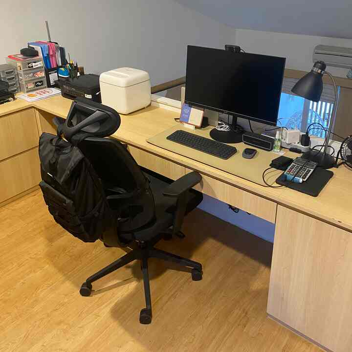 Wood tone floor and desk with a black office chair in a compact loft home office space