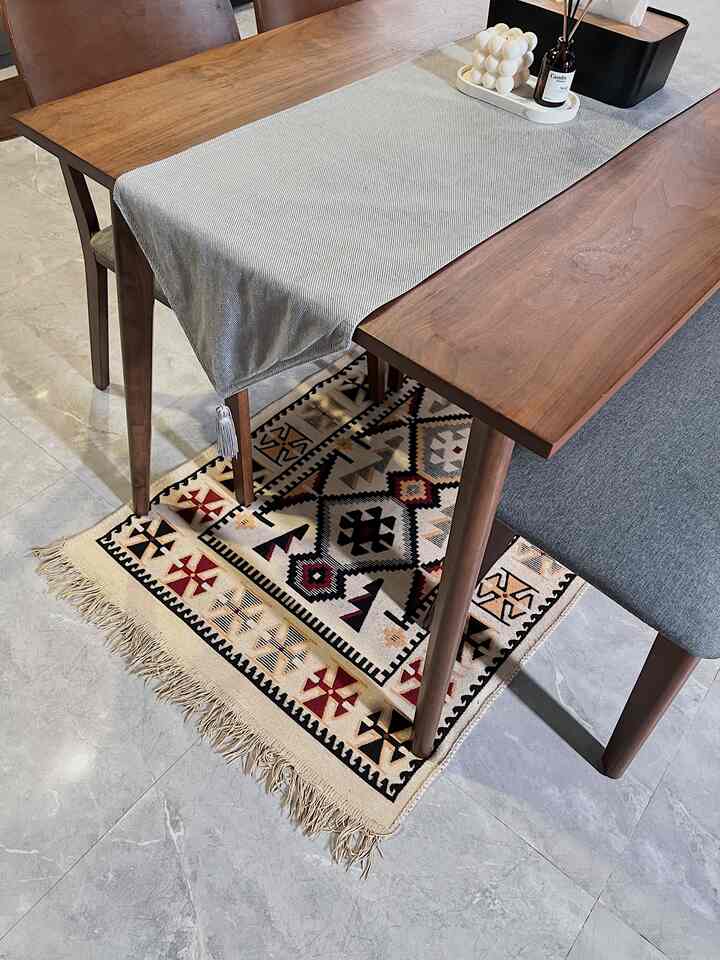 Dining room with brown wooden dining table and patterned rug, set against monotone tiled floor for sleek interior