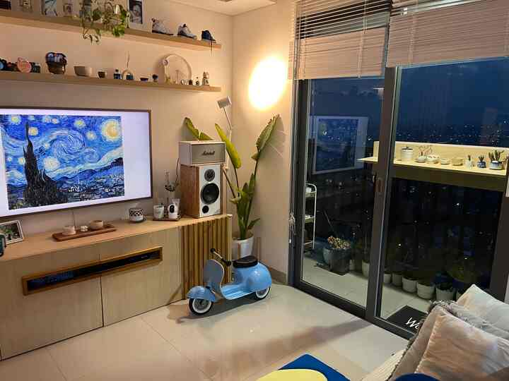 Natural color and blue toned living room featuring sofa, large smart TV, and plants with a cozy atmosphere