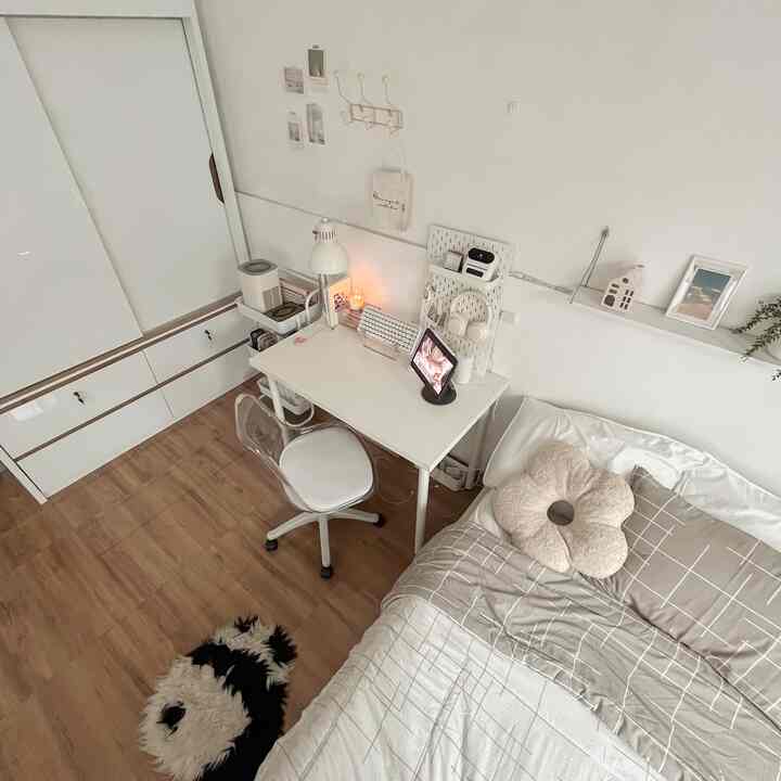 A compact bedroom in white and natural tones, featuring a simple desk and office chair creating a cozy atmosphere