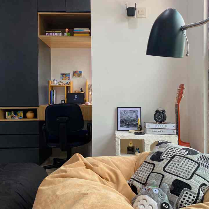 Simple home office space with beige bean bag sofa and black office chair, wood shelves and adorable Totoro figurines in a cozy room