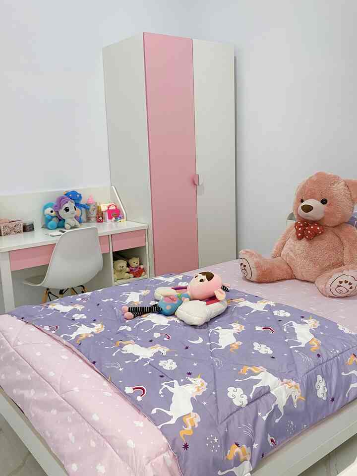 Pink and white toned kids' room featuring pink wardrobe and desk with playful toys and bedding