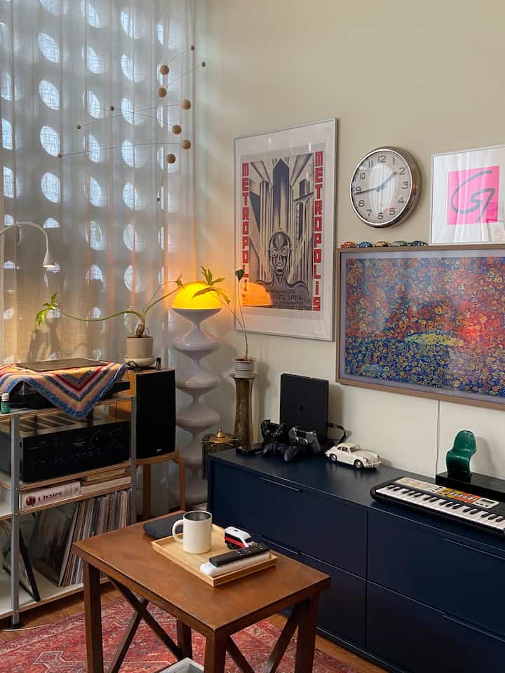 Mid-century modern living room with warm wood tones flooring and navy cabinet, featuring stylish framed art and unique lighting