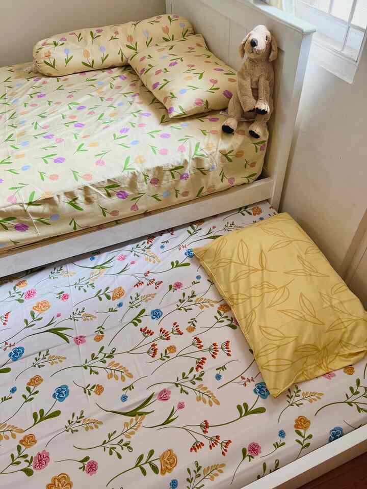 Natural, cozy kids' room featuring two beds with cream and multicolor floral bedding near bright window