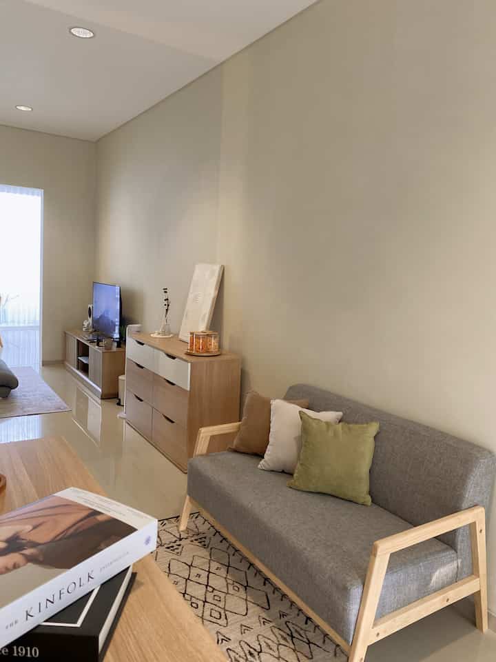 Beige and wood tone living room with a gray sofa and cushions creating a warm, natural modern atmosphere