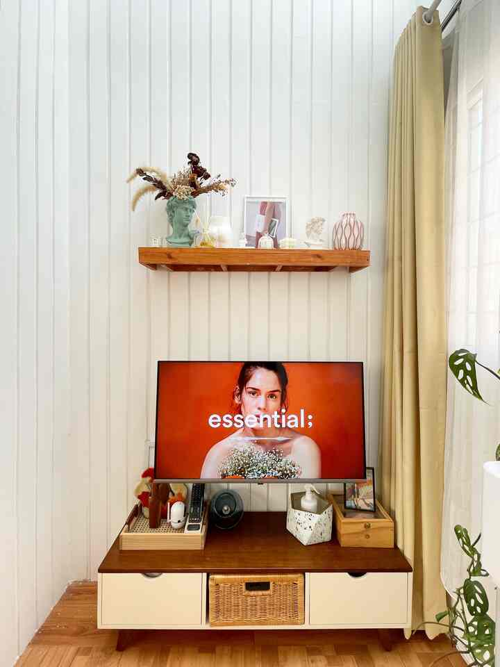 Living room with dominant white walls and natural wood tone furniture, featuring a TV and various vases for a cozy atmosphere