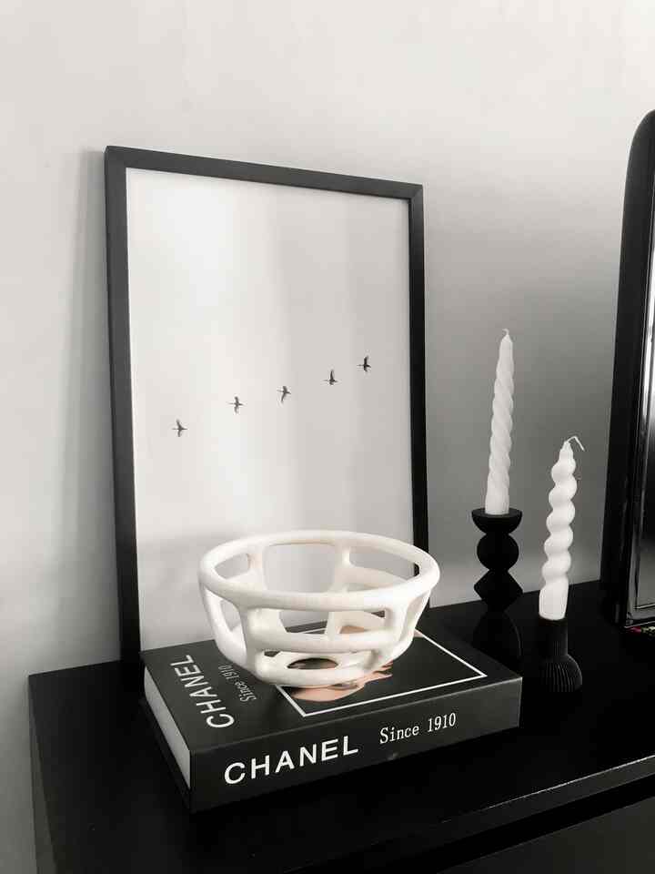 Monotone living room featuring a black picture frame, white objet, and twisted candles with minimalist decor