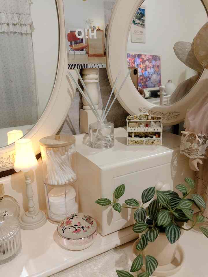 Natural tone vanity area with mirrors, table lamp, and a potted plant creating a cozy atmosphere