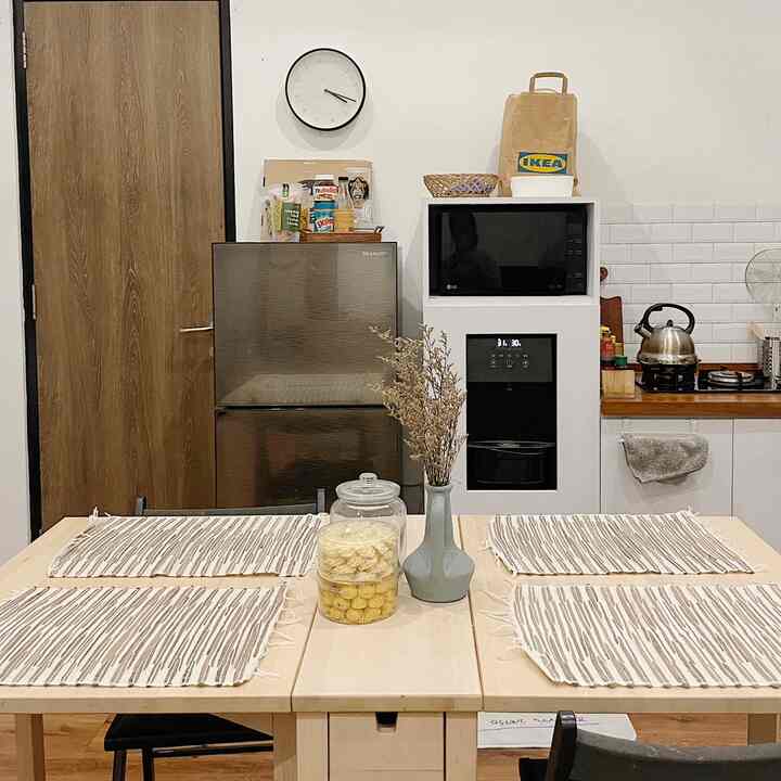 Wood tone and white kitchen featuring a 4-person dining table with placemats and neatly arranged tableware, creating a cozy atmosphere