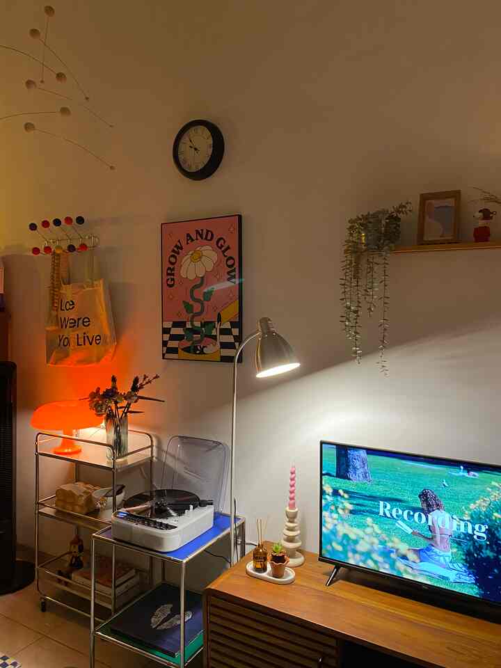 Cozy living room with warm orange lighting and mid-century modern furniture, featuring retro audio equipment and art poster accents
