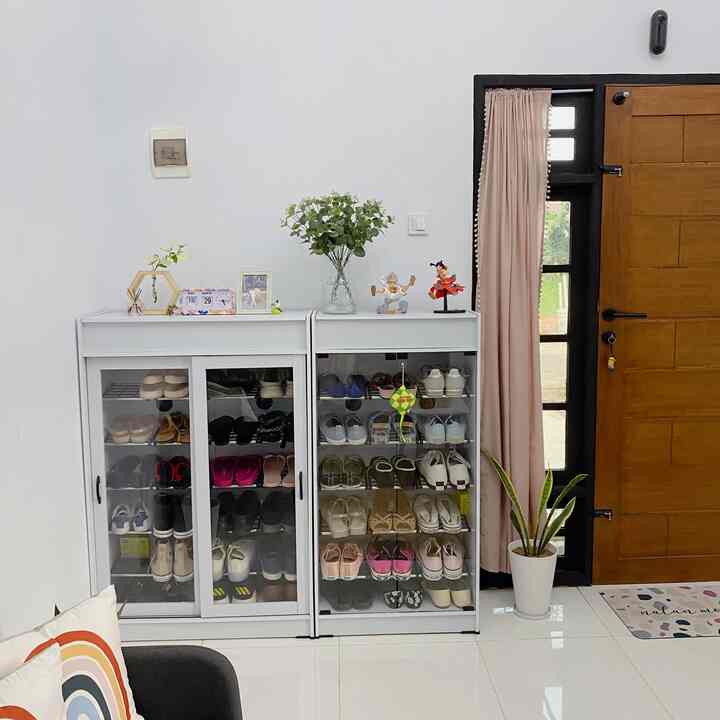 White and brown toned living room corner featuring shoe cabinets and plant with a clean, simple atmosphere