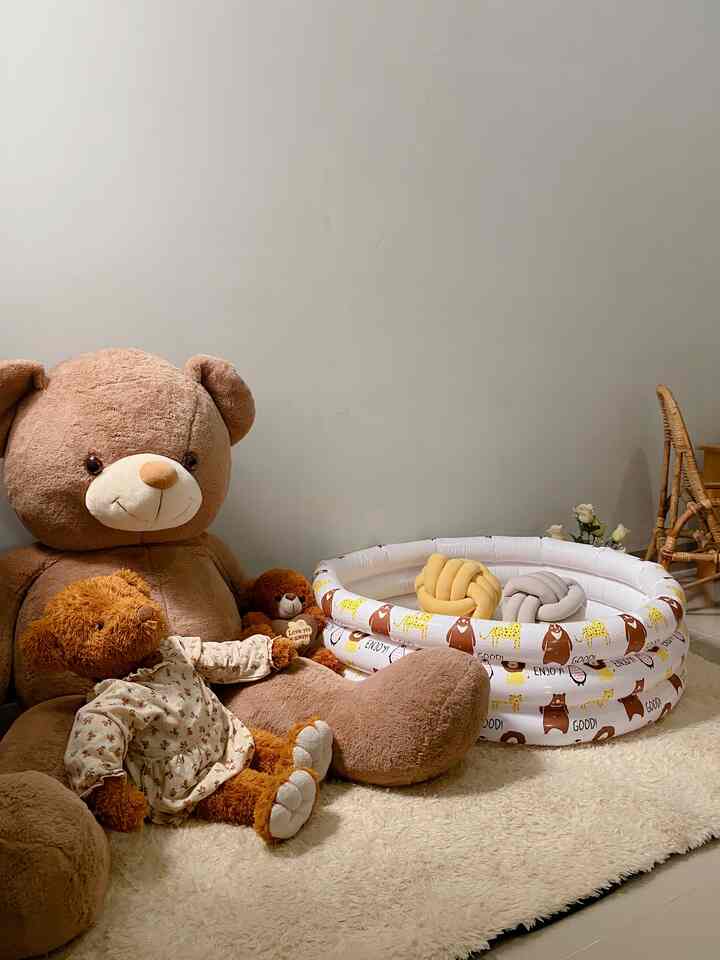 Beige and brown toned kids' room featuring large teddy bears, fluffy carpet, and a small round play pool, creating a cozy atmosphere