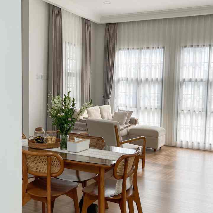 Natural tone dining and living room with wooden dining table and beige curtains in a cozy space