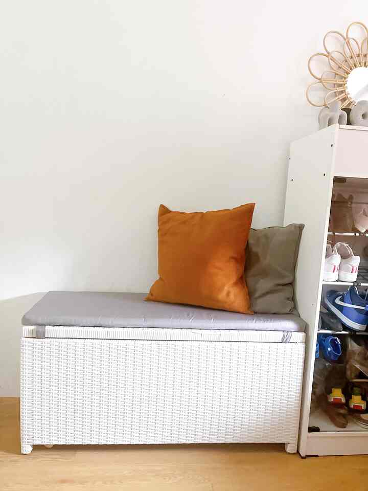 Bright white and natural brown toned entrance mudroom featuring rattan bench and shoe cabinet with a cozy atmosphere