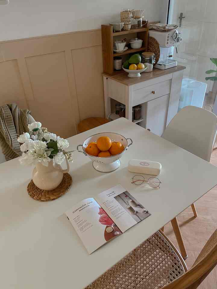 Natural brown and white toned kitchen corner featuring dining table, chairs, coffee machine, and cozy accessories