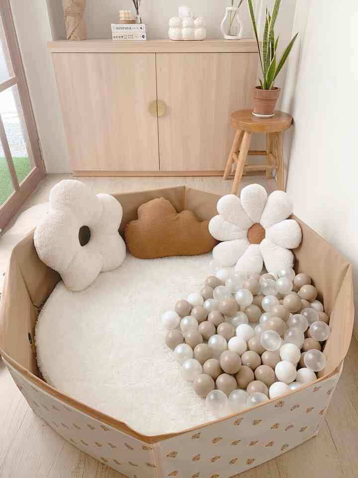 Natural beige-tone kids' room featuring a ball pit filled with beige and white balls and flower-shaped cushions creating a cozy play area