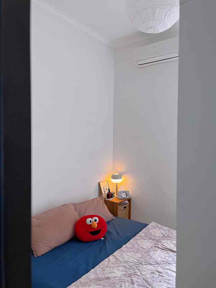 Small bedroom with white walls and navy bedding, featuring brown nightstand and lamp creating cozy atmosphere
