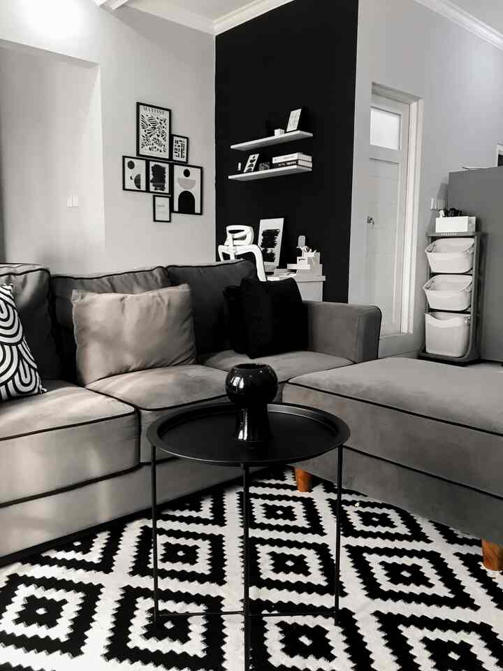 Monotone living room featuring a large sectional sofa and geometric patterned rug with a sleek atmosphere