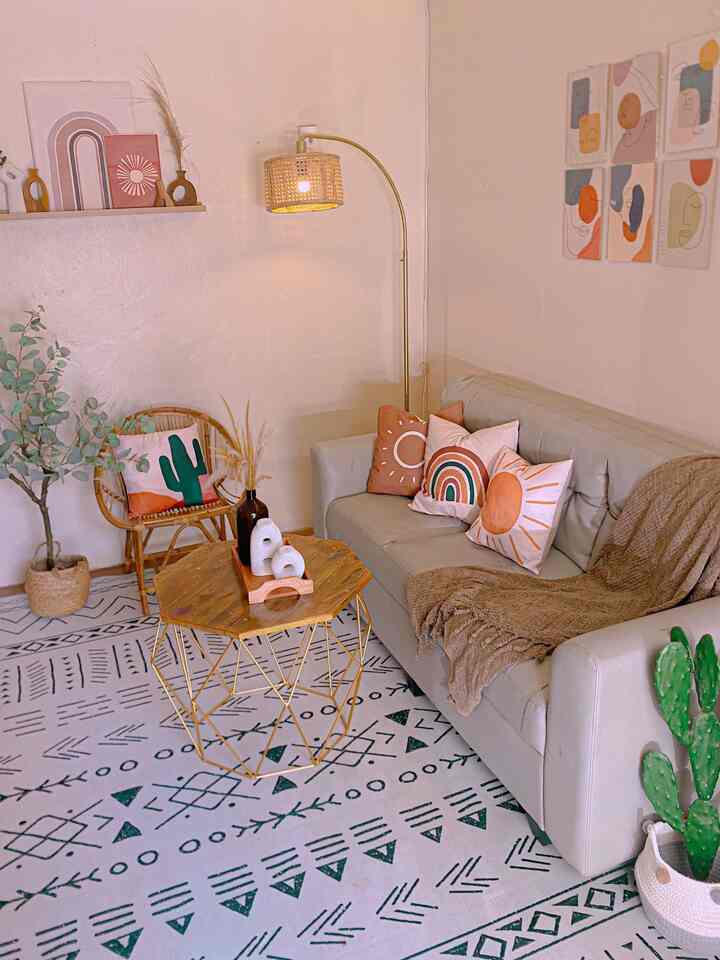 Natural color toned living room featuring a gray sofa, wooden coffee table, patterned rug, floor lamp, and wall art creating a cozy atmosphere