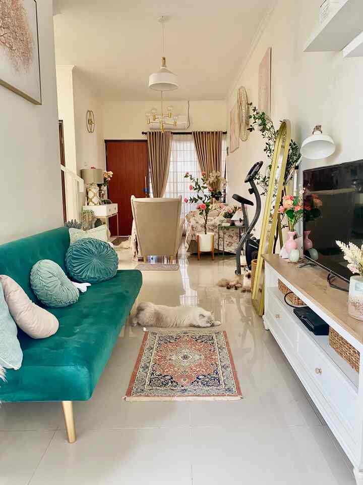 White and gold toned living room featuring green sofa and flower decorations with a cozy vintage atmosphere