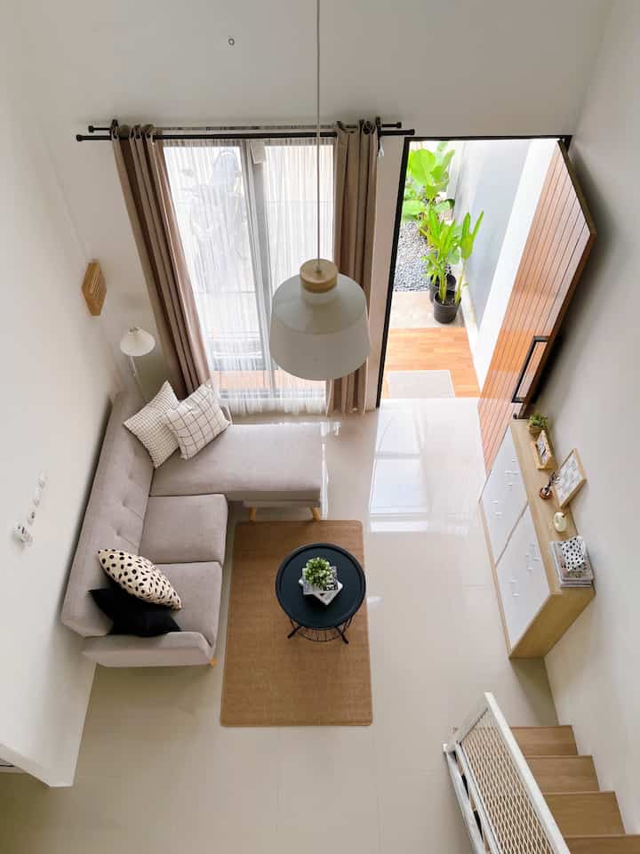 White and wood tone living room featuring beige sofa and round black coffee table with a clean, simple atmosphere