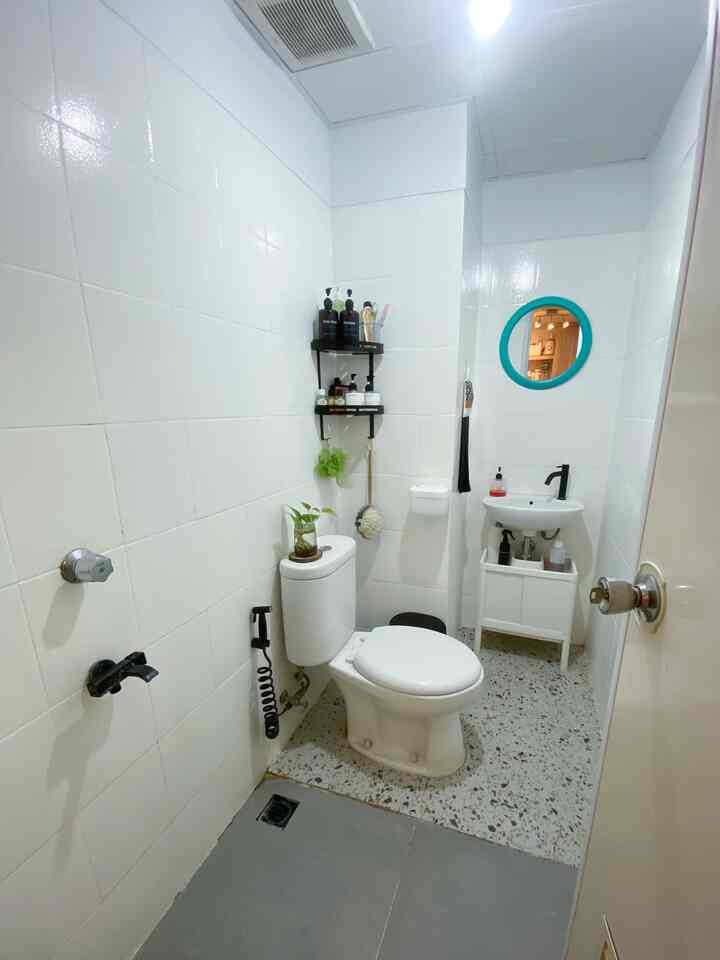 White-toned narrow and long bathroom featuring a toilet and a sink with minimalistic style