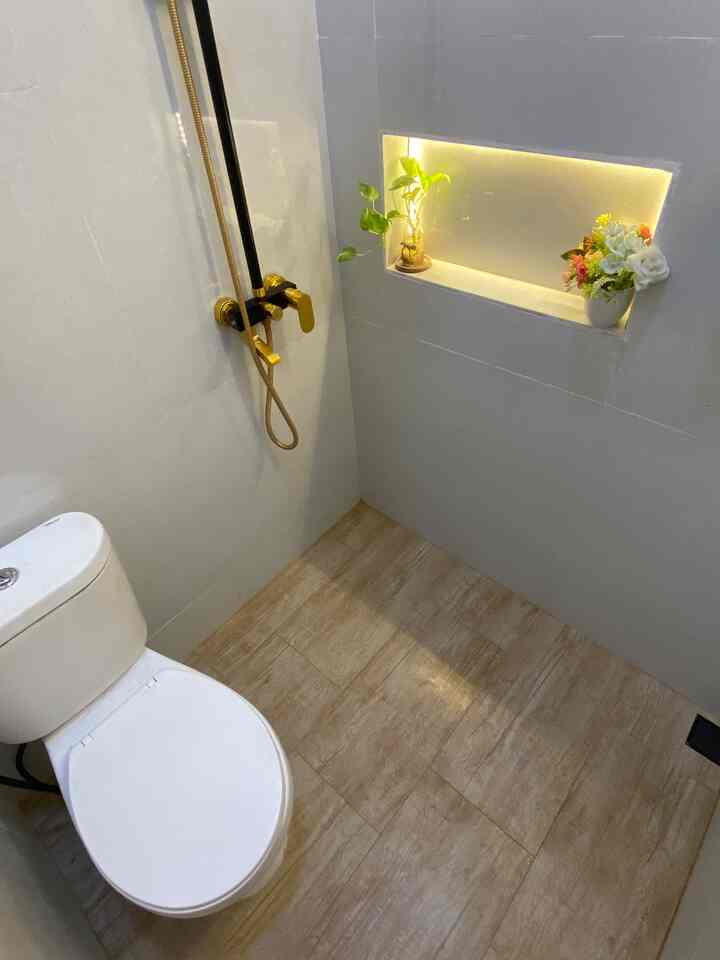 White and beige toned square bathroom featuring gold fixtures and wood-tone floor, creating a simple and harmonious space