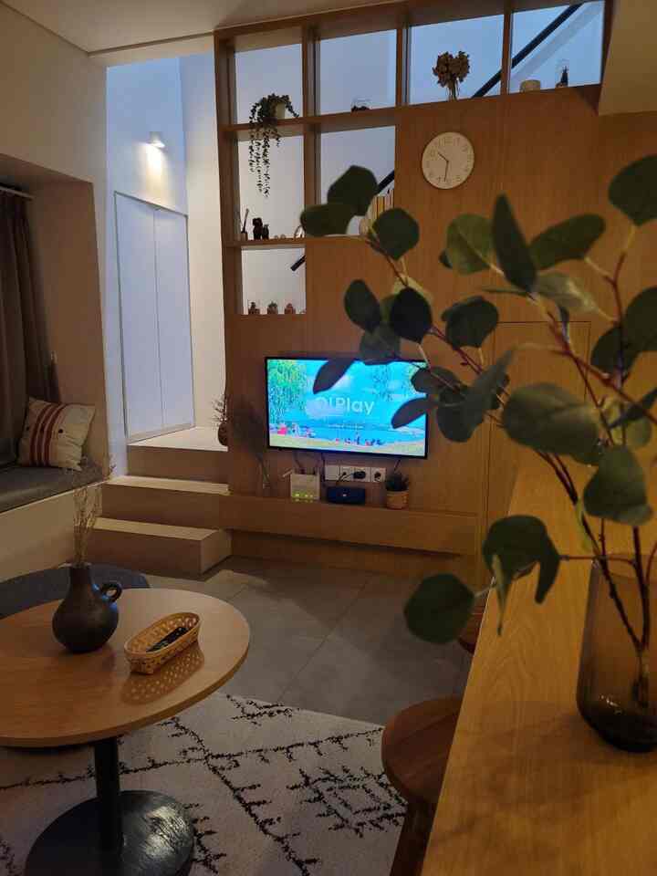 Wood tone and white living room featuring a round coffee table and wall-mounted TV with cozy atmosphere
