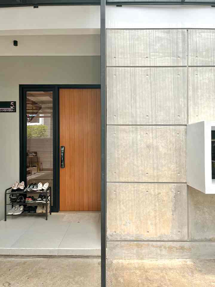White and gray toned industrial style entrance featuring wood-tone door and black accents in a simple design