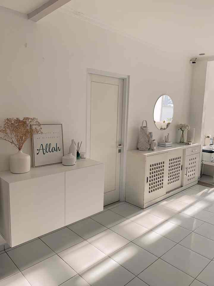 Bright white-toned entrance area featuring a central door and two white cabinets on each side with a clean storage idea focus