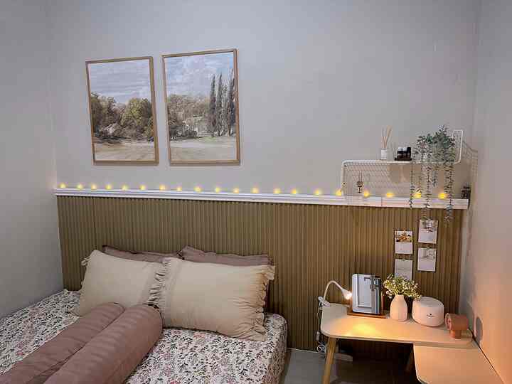 Beige and white toned square bedroom featuring floral bedding, a desk with warm lighting, and plant decorations creating a cozy atmosphere