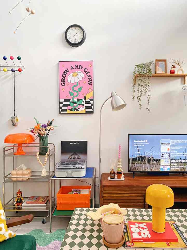 Colorful living room with dominant orange and green tones, featuring checkered tablecloth and distinctive lamps in a bright artistic setting