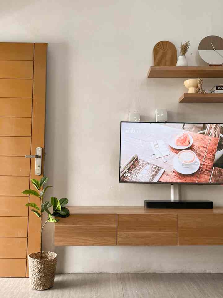 Living room with white walls, wood tone furniture, and a plant, creating a warm and clean atmosphere