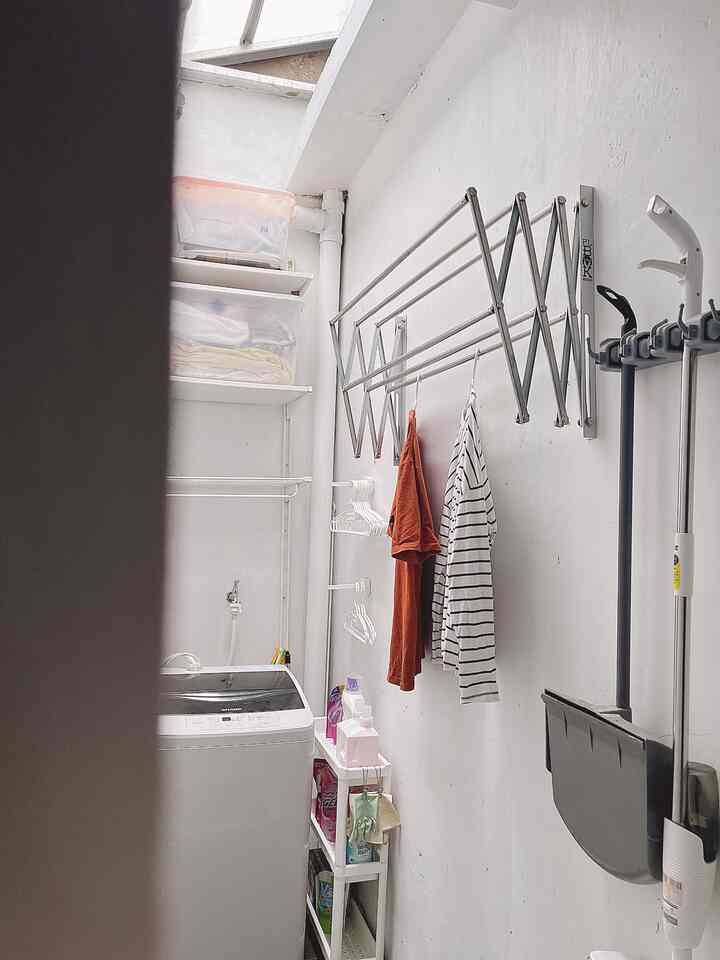 White-toned narrow laundry corner with wall-mounted drying rack and storage cart, practical and well-ventilated space