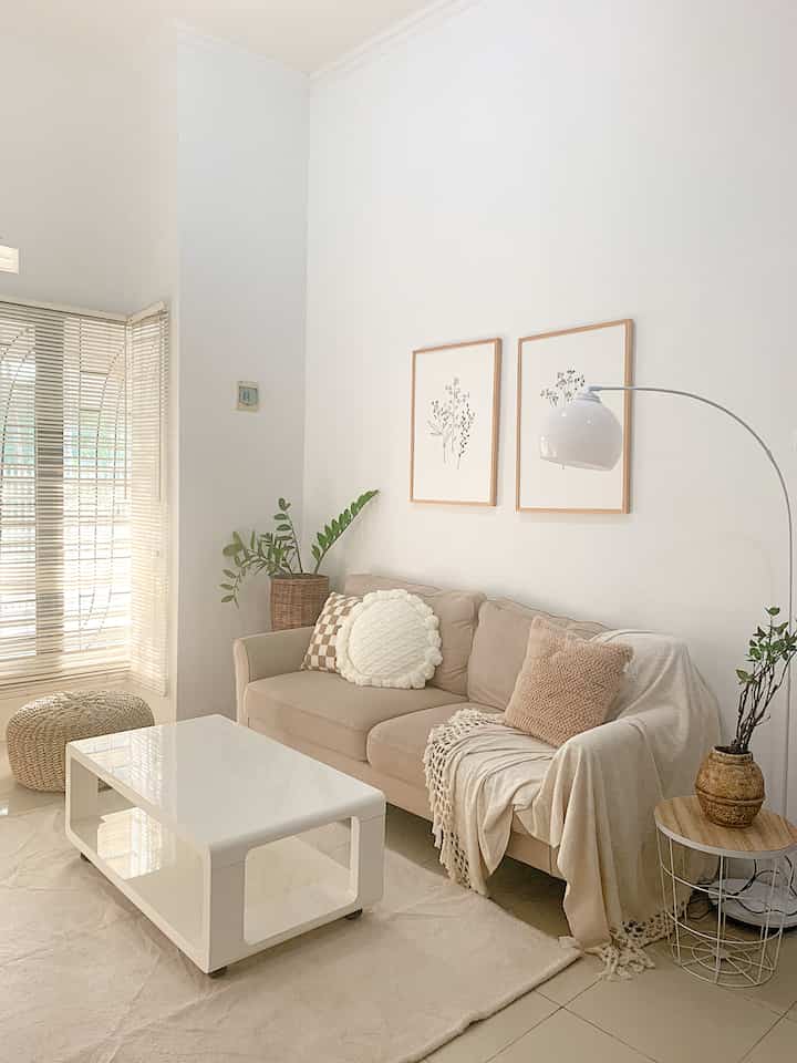 Beige and brown toned living room featuring cozy sofa, white coffee table, and natural decor with a warm atmosphere