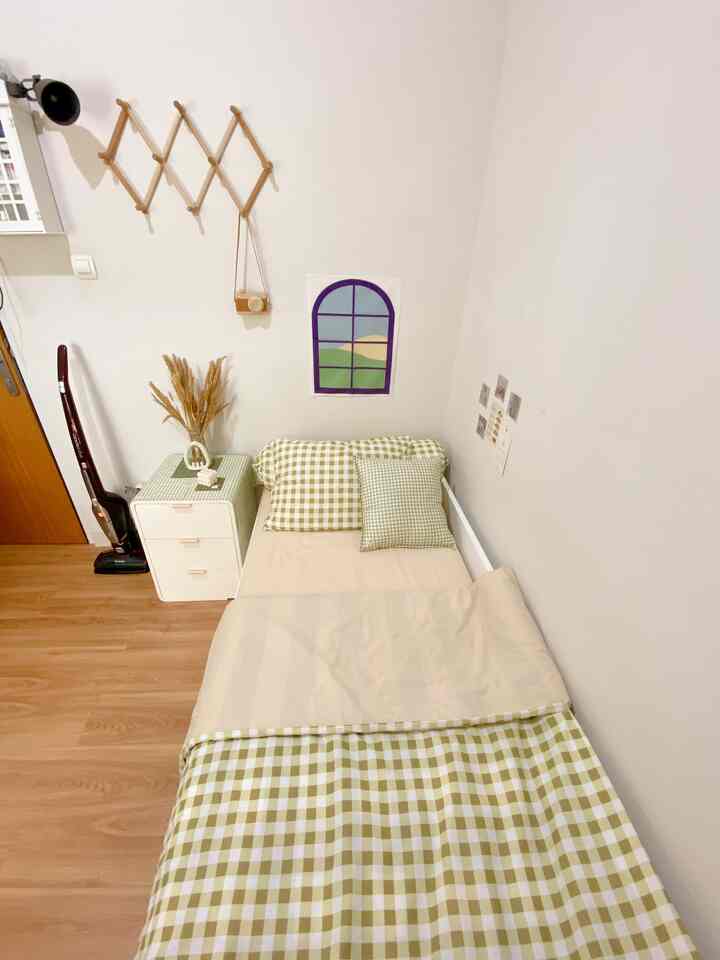 Natural color tones and wood floor in a small, simple bedroom featuring a bed and dresser for single household