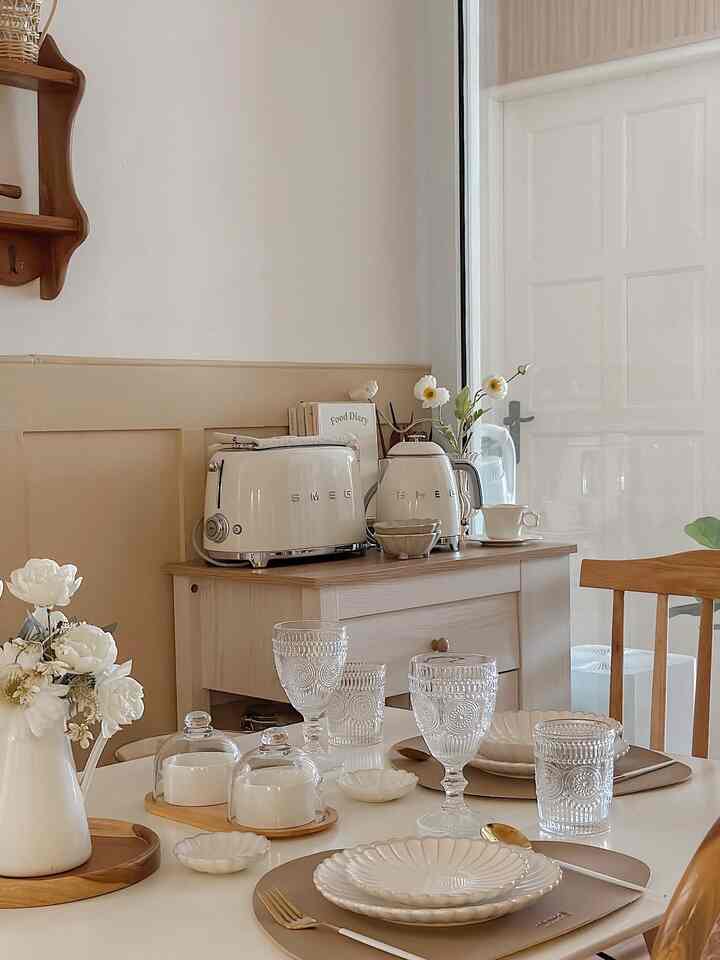 Beige and white toned kitchen featuring a dining table with minimalistic table setting creating a cozy atmosphere