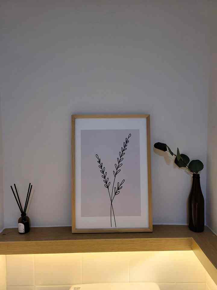 Natural wood shelf displaying minimalist plant art and diffuser in a compact, long and narrow powder room