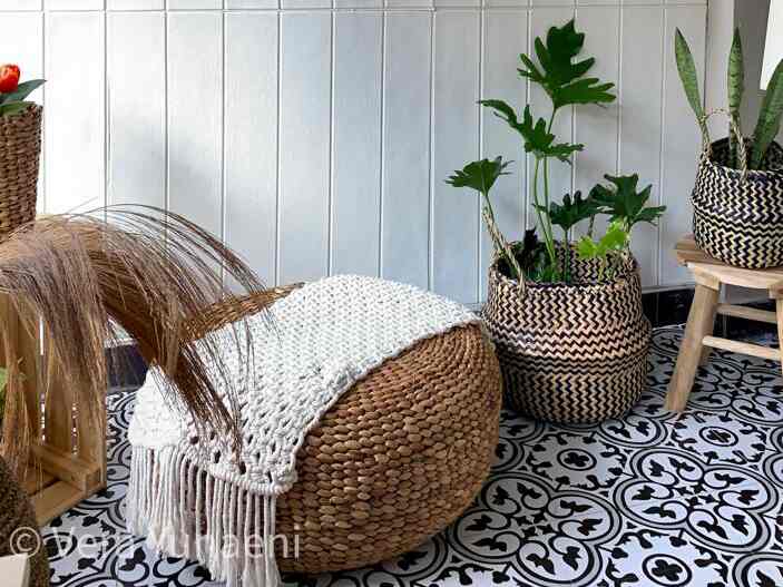 Natural beige-toned balcony featuring a rattan pouffe and green plants, creating a cozy atmosphere