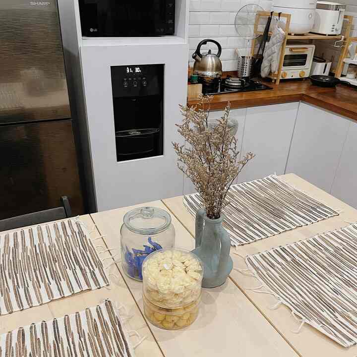 Natural-toned 3x4 meter kitchen featuring wood countertops, white cabinets, four-person dining table and dried floral centerpiece creating warm atmosphere
