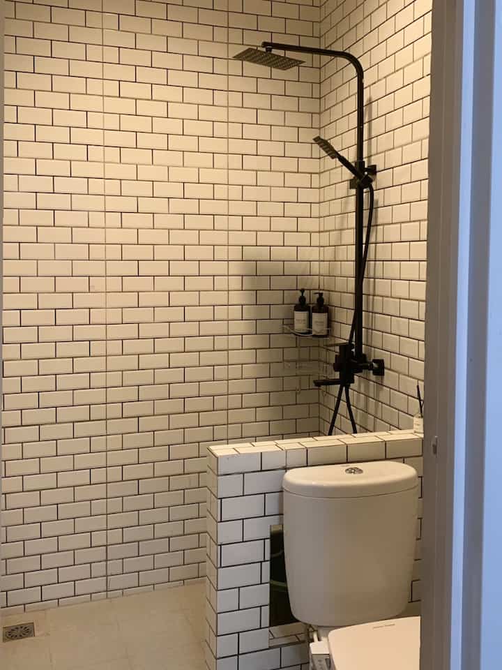 White tiled bathroom with black shower set featuring semi-industrial style