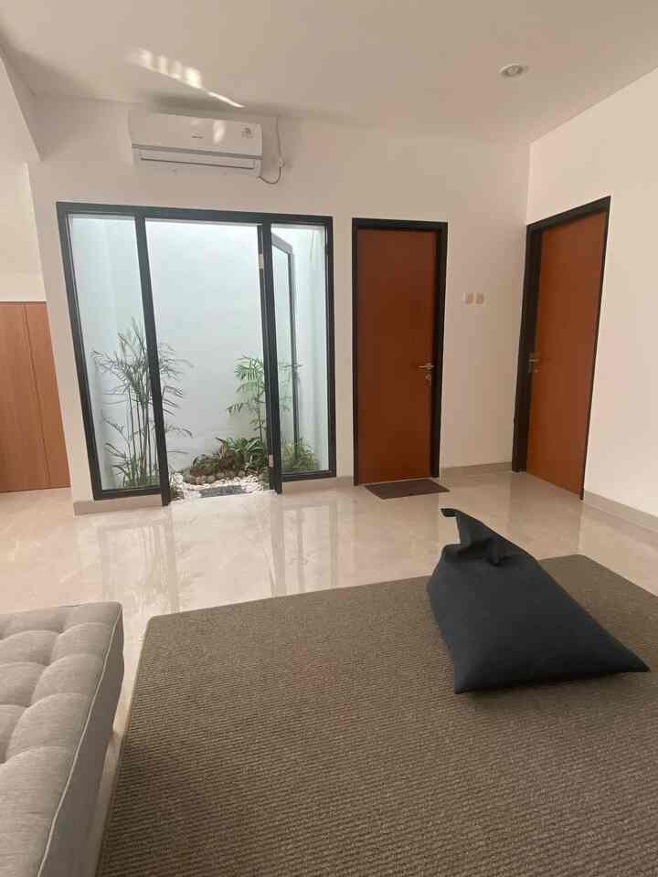 Bright white-walled modern living room featuring brown doors, large glass doors, and a spacious carpet creating openness